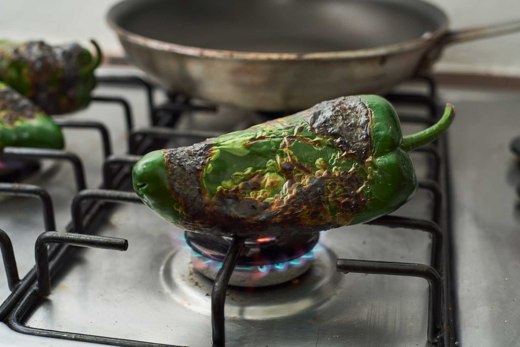 Poblano pepper charring on an open flame on the stovetop